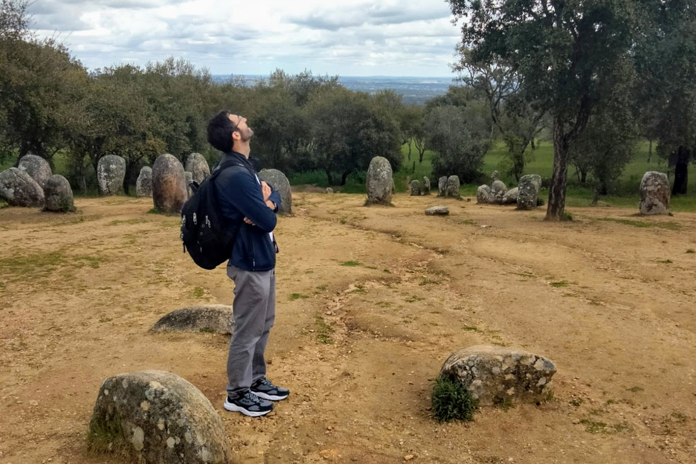Man standing in an ancient cairn circle, staring up