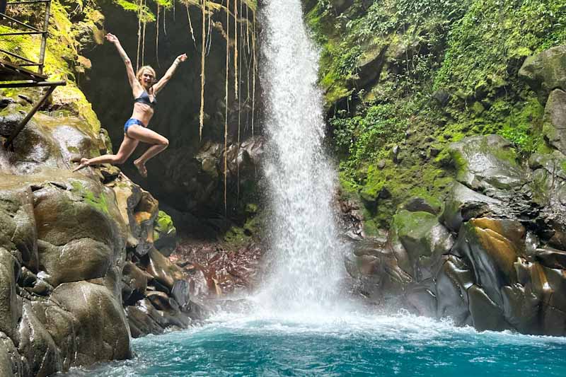 Woman jumping into a pool with waterfall