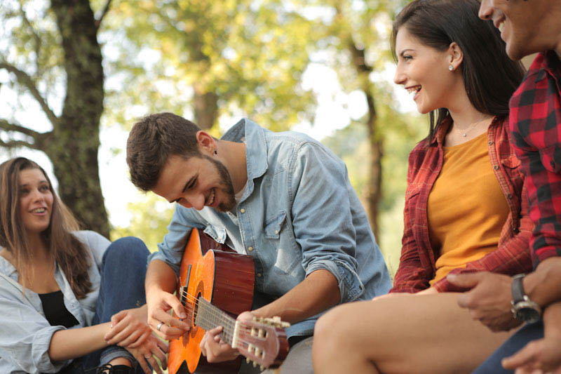 Happy young people playing guitar outside